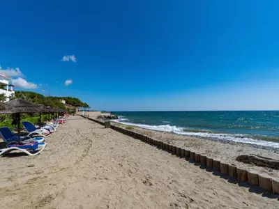 a beach with chairs and umbrellas and the ocean at Vacances en Corse in San-Nicolao
