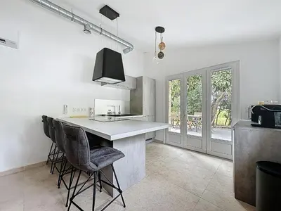 a kitchen with a counter and some chairs in it at Villa 2 chambres avec jacuzzi in Bonifacio