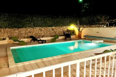 a swimming pool at night with chairs and a table at Villa de charme Porto-Vecchio, Plage à 10 min in San-Gavino-di-Carbini