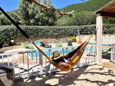 a person laying in a hammock next to a pool at Villa de charme Porto-Vecchio, Plage à 10 min in San-Gavino-di-Carbini