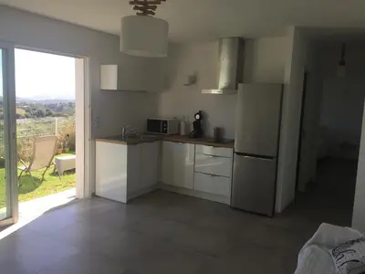 a kitchen with a white refrigerator and a window at Charmant T2 en rez de villa, neuf, tout équipé, indépendant avec jardin attenant in Afa