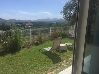 a living room with a couch and a kitchen at Charmant T2 en rez de villa, neuf, tout équipé, indépendant avec jardin attenant in Afa