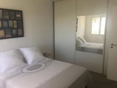 a bed with white sheets and a picture on the wall at Charmant T2 en rez de villa, neuf, tout équipé, indépendant avec jardin attenant in Afa