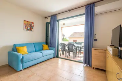 a living room with a blue couch and a sliding glass door at La Marine de Bravone in Linguizzetta