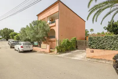 a building with cars parked on the side of a street at La Marine de Bravone in Linguizzetta