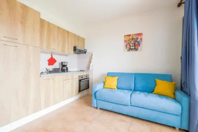 a blue couch in a kitchen with yellow pillows at La Marine de Bravone in Linguizzetta