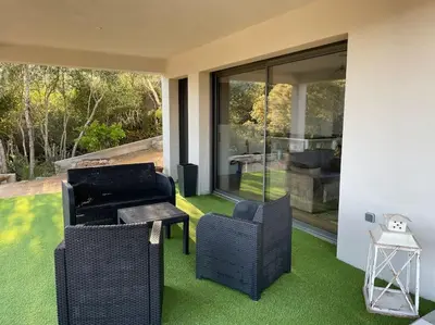 a patio with two chairs and a table and some grass at T2 très bien équipé vue mer et au calme in Ajaccio