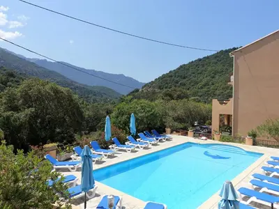 a swimming pool with lounge chairs and umbrellas at Studio Residence Cabanaccia Studio 38m² by Interhome in Serriera