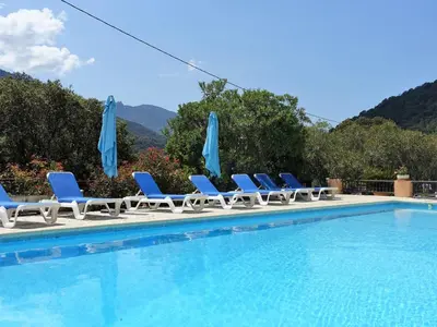 a group of chairs and umbrellas next to a swimming pool at Studio Residence Cabanaccia Studio 35m² by Interhome in Serriera