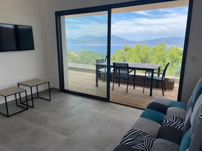 a living room with a couch and a table and a balcony at LOCA VACANCES in Porticcio