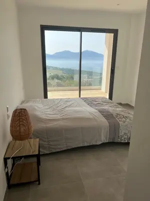 a bedroom with a bed and a large window at LOCA VACANCES in Porticcio