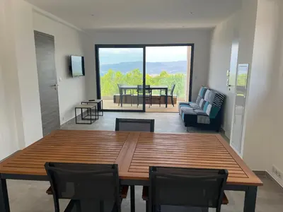 a living room with a wooden table and chairs at LOCA VACANCES in Porticcio