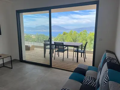 a living room with a table and chairs on a balcony at LOCA VACANCES in Porticcio