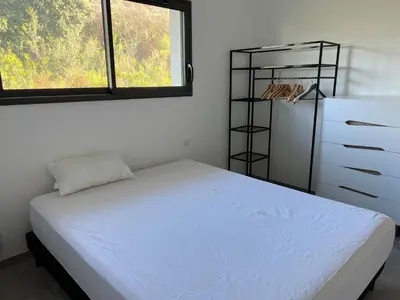a bedroom with a bed and a dresser and two windows at LOCA VACANCES in Porticcio