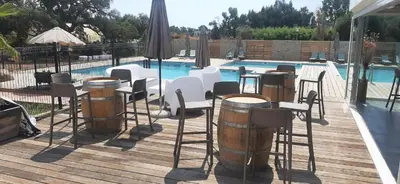 a deck with chairs and barrels next to a swimming pool at Appartement T2 en Corse dans résidence avec piscines proche de Porto Vecchio in Lecci