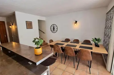 a dining room with a table and chairs and a clock at Plage à pied : Mini villa Saint-Cyprien in Lecci