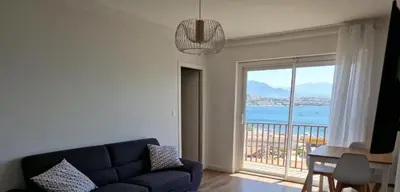 a living room with a blue couch and a large window at Vista mare in Ajaccio