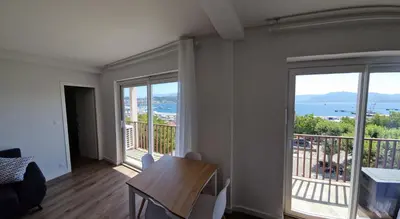a living room with a table and a balcony at Vista mare in Ajaccio