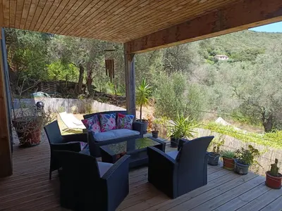 a patio with a couch and chairs on a deck at T3 en rez de villa sur les hauteurs d'Ajaccio in Ajaccio