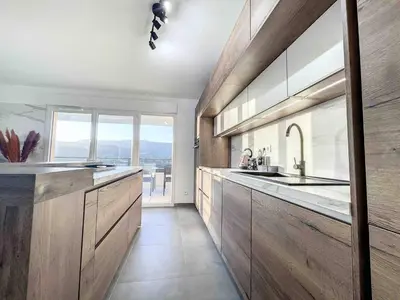 a kitchen with wooden cabinets and a large window at Appartement central avec très jolie vue in Ajaccio