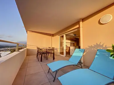 a balcony with blue chairs and a table at Appartement central avec très jolie vue in Ajaccio