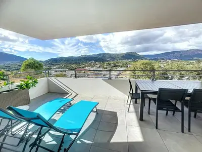 a balcony with a table and chairs and mountains at Appartement central avec très jolie vue in Ajaccio