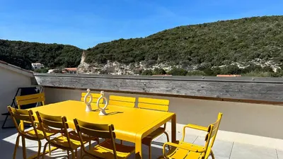 a yellow dining table and chairs on a balcony at Sur le port, 150m2 - Parking gratuit, Climatisation, Terrasses - Standing in Bonifacio