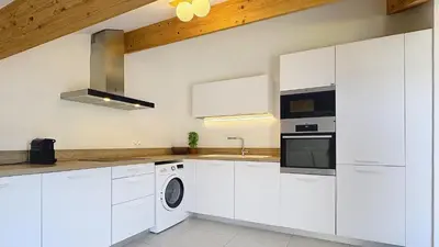 a kitchen with white cabinets and a washer and dryer at Sur le port, 150m2 - Parking gratuit, Climatisation, Terrasses - Standing in Bonifacio