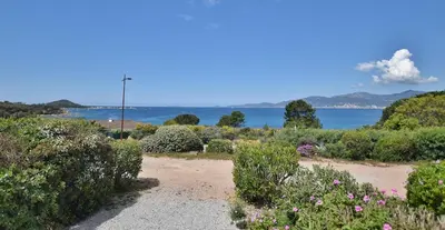 a garden with flowers and the ocean in the background at mare noi in Pietrosella