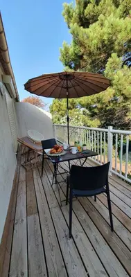 a table and chairs and an umbrella on a deck at Fiori Di Cala Rossa Appartement T3 dans résidence hôtellière chez Virginie in Lecci