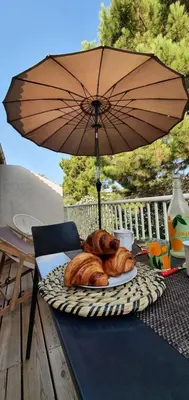 a plate of bread and an umbrella on a table at Fiori Di Cala Rossa Appartement T3 dans résidence hôtellière chez Virginie in Lecci