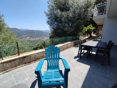 a blue chair sitting on a patio with a table at Farniente e Dolce vita in Olmeto