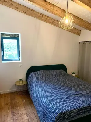a bedroom with a blue bed and a window at Caseddu au coeur du village in Monacia-dʼAullène