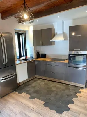 a kitchen with stainless steel appliances and a wooden floor at Caseddu au coeur du village in Monacia-dʼAullène