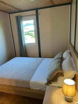 a bedroom with a bed with a window and a lamp at La vallée 2 in Belvédère