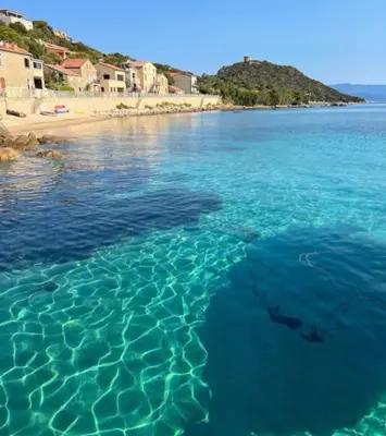 a body of water with a beach in the background at La vallée 2 in Belvédère