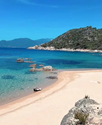 a beach with blue water and rocks in the ocean at La vallée 2 in Belvédère