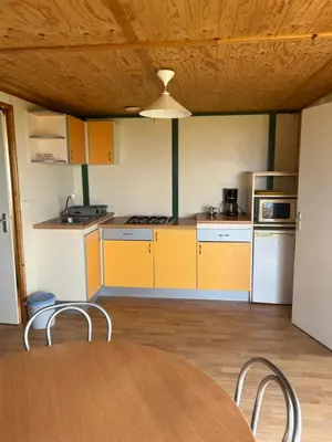 a kitchen with yellow cabinets and a table and chairs at La vallée 2 in Belvédère