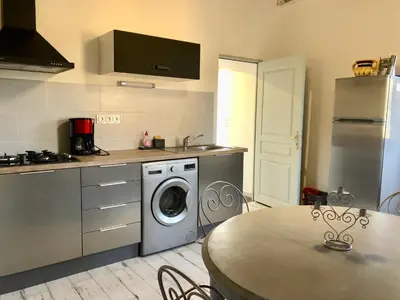 a kitchen with a washing machine and a table at Appartements de Charme in Corte