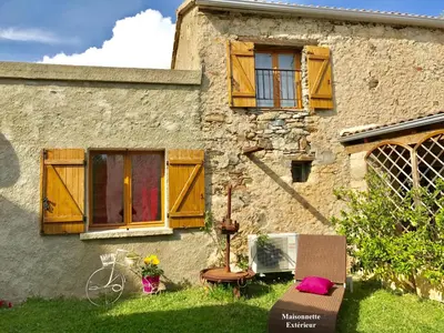 a house with wooden windows and a chair in the yard at Appartements de Charme in Corte