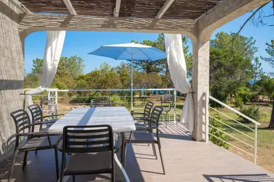 a patio with a table and chairs and an umbrella at Domaine de Pianiccia in Favone