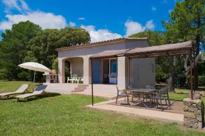 a house with a table and chairs and an umbrella at Domaine de Pianiccia in Favone