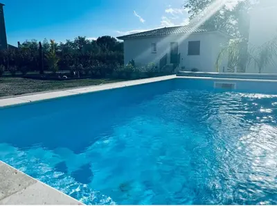 a swimming pool with blue water in front of a house at Villa mina in Ghisonaccia