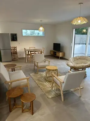 a living room with chairs and tables and a tv at Villa mina in Ghisonaccia