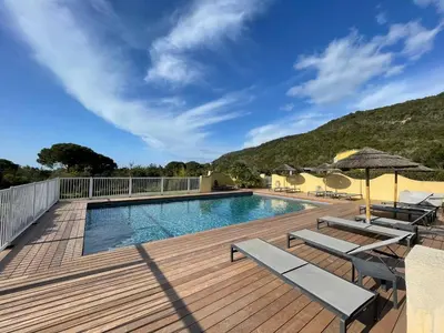 a swimming pool on a wooden deck with chairs and umbrellas at CASA PALOMBAGGIA - Piscine Chauffée in Porto-Vecchio