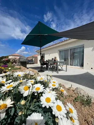a woman sitting at a table under a green umbrella at A PIAZZOLA in Petreto-Bicchisano