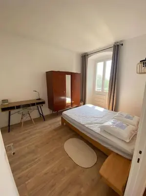 a bedroom with a bed and a desk in it at Corte magnifique T2 45m2 neuf 5 personnes place st marcel hyper centre wifi lave linge tv in Corte
