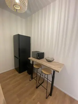 a table with two stools and a black refrigerator at Corte magnifique T2 45m2 neuf 5 personnes place st marcel hyper centre wifi lave linge tv in Corte