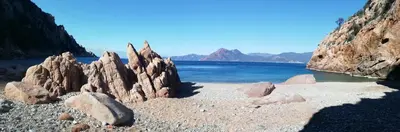 a group of rocks on a beach near the water at A Torra in Ville-di-Paraso