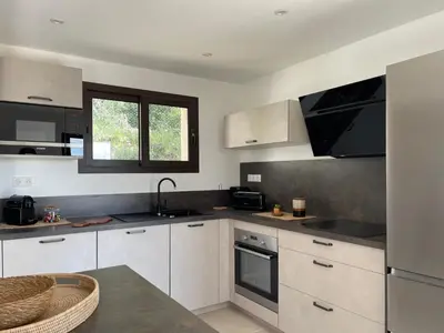 a kitchen with white cabinets and black counter tops at Les Hauts de Capo - Domaine privé à proximité de Porto-Vecchio in Lecci
